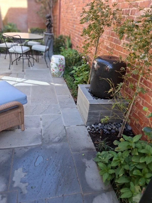 Stone paving, planted borders, and a decorative water feature.