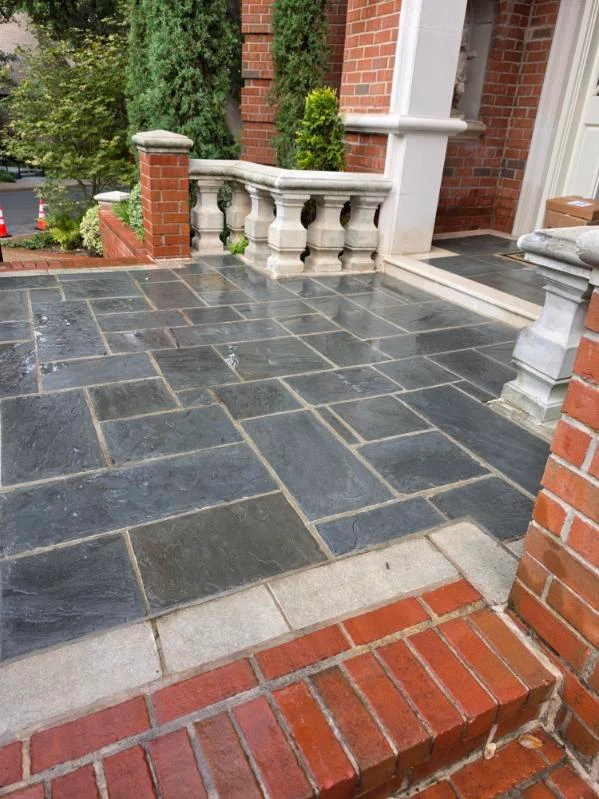 Rectangular stone paving finishes a terrace beside brick steps and a balustrade.