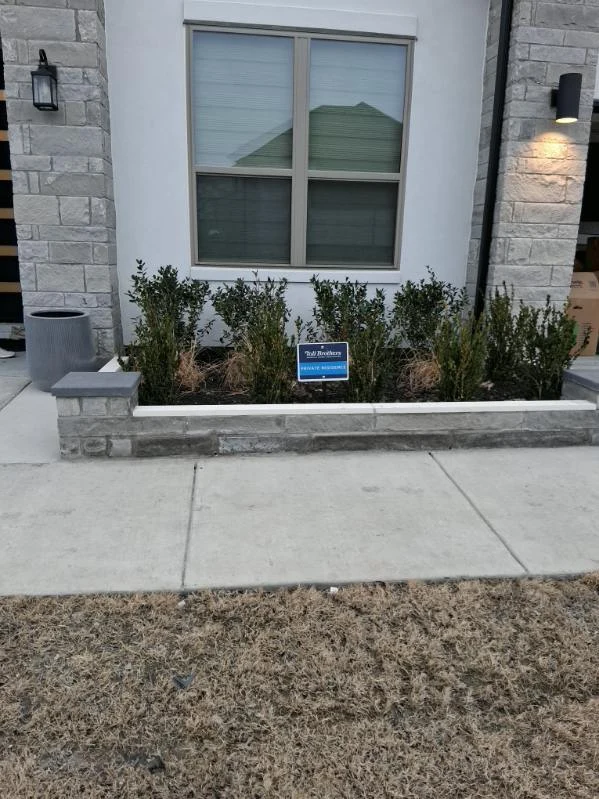 A stone border frames shrubs beneath a front window.
