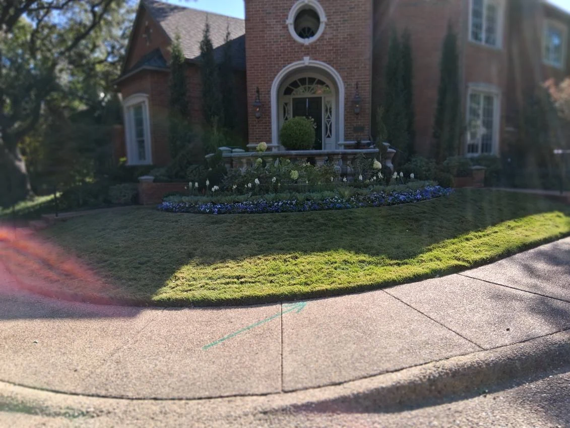 A sweeping flower bed follows the front lawn below a brick entrance.