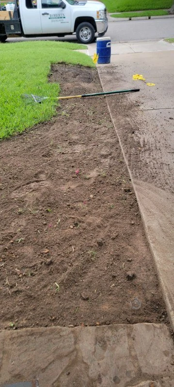 Exposed soil beside the driveway shows a landscape work area being prepared.