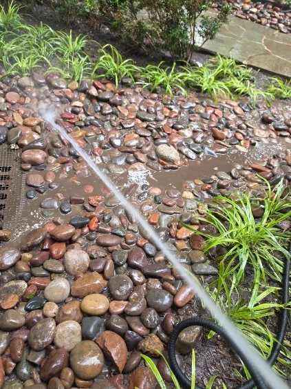 A hose runs across wet river rock during drainage work.
