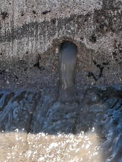 Water flows from a drainage outlet into the collection area below.