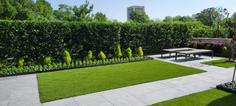 Artificial turf and large paving stones define a garden seating space.